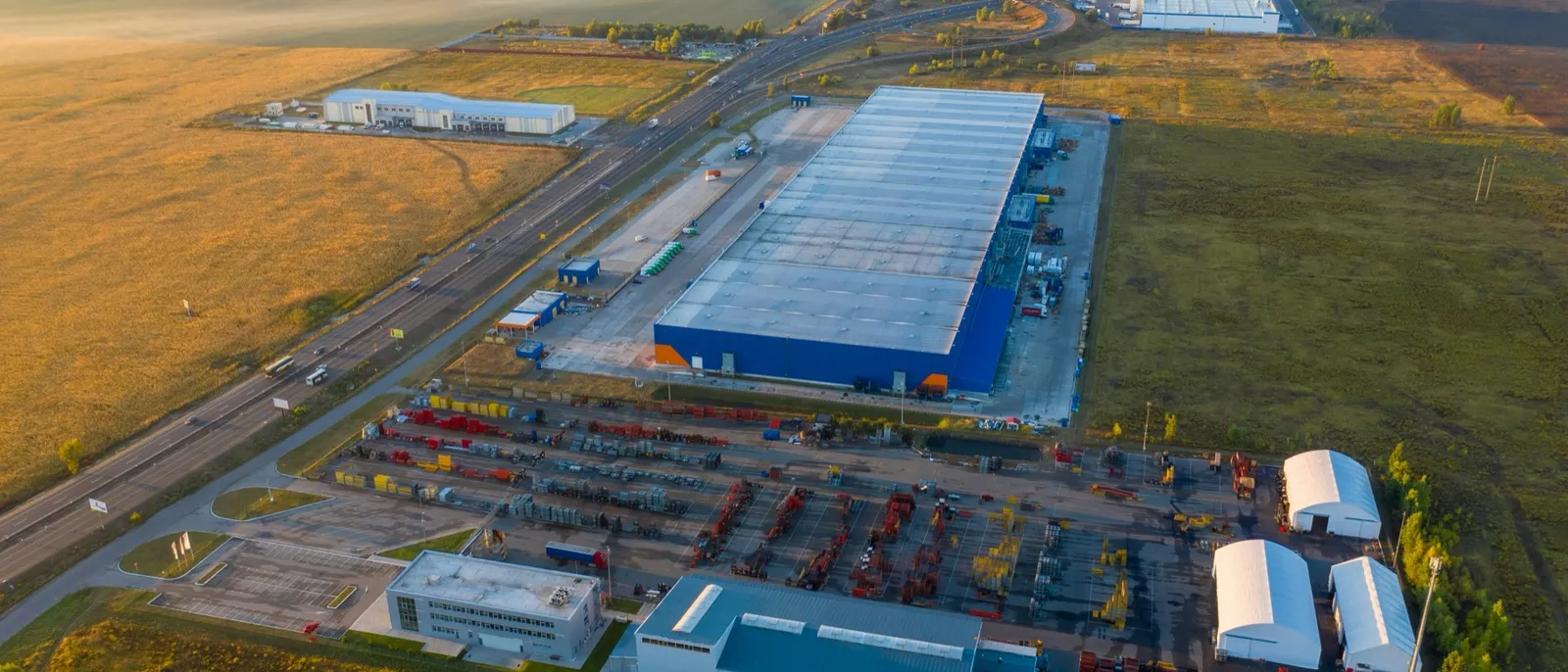 Aerial view of an industrial campus beside open farmland at dawn
